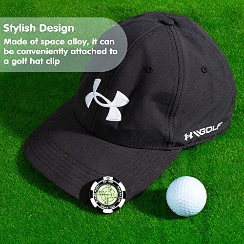 Black golf hat with logo, ball, and clip on grass.